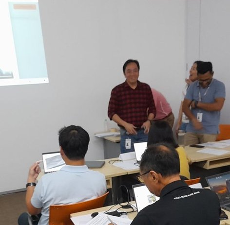 A participant presenting how their team used AI to solve a workplace problem, at the end of a QuestAI Technologies training session